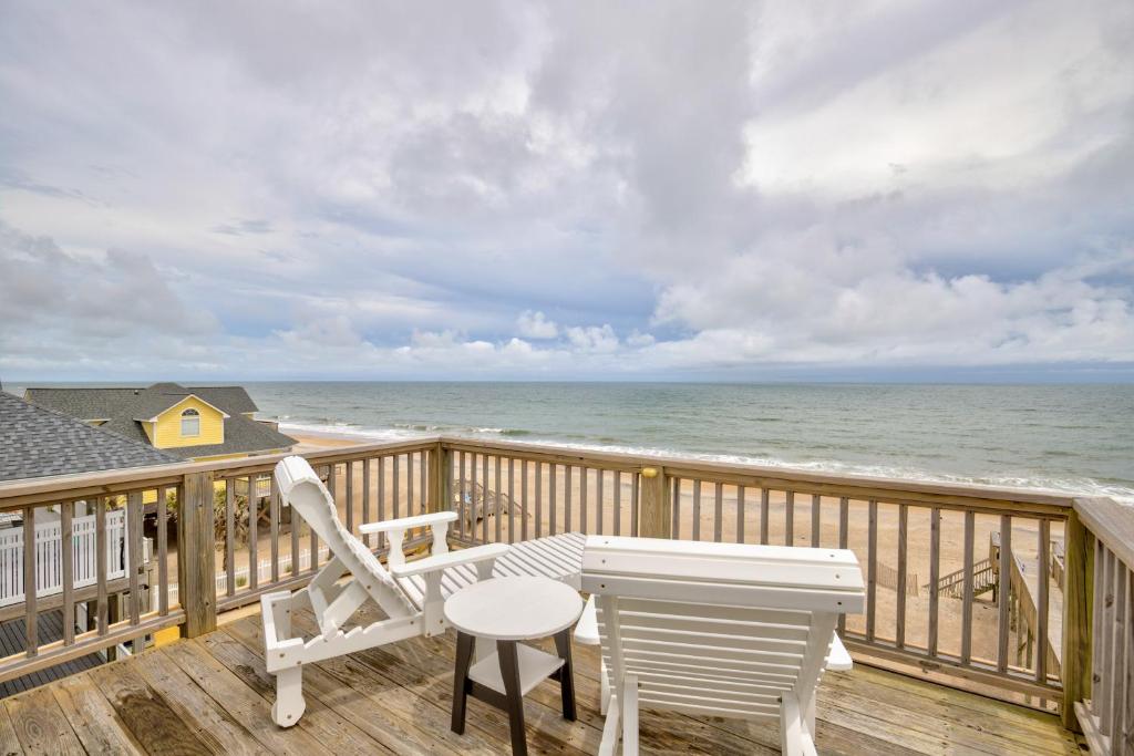 a deck with a table and chairs and the ocean at The Lazy Beagle in North Topsail Beach