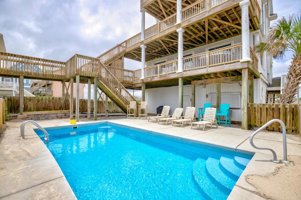 a swimming pool with chairs and a house at The Lazy Beagle in North Topsail Beach