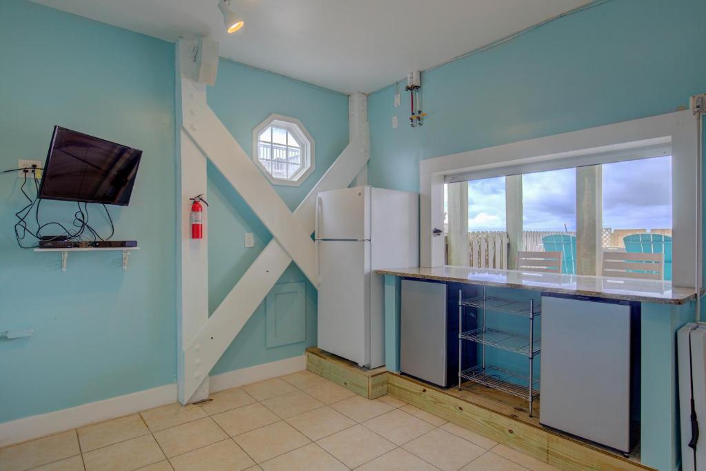 a kitchen with blue walls and a tv on the wall at The Lazy Beagle in North Topsail Beach