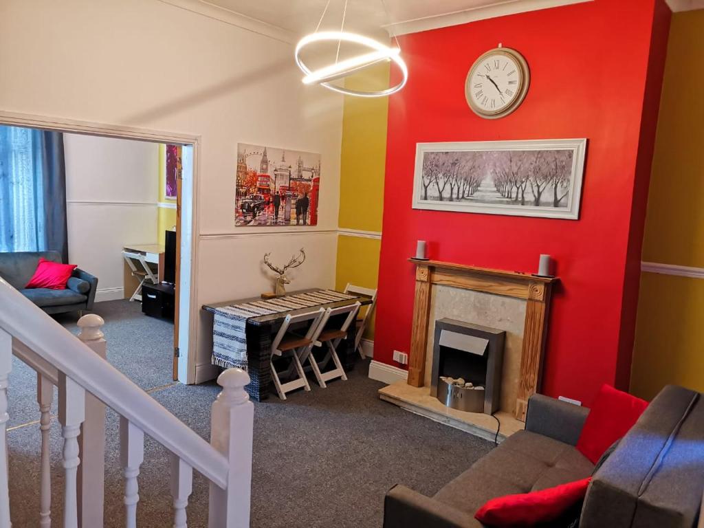 a living room with a red wall and a fireplace at The Superhost - 4 BR House in Sunderland