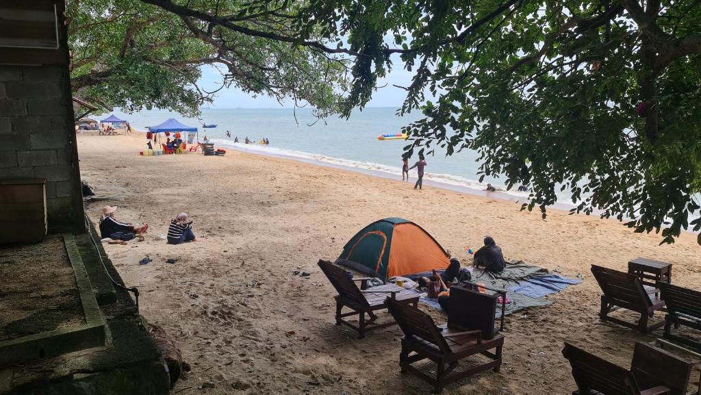 a group of people sitting on a beach with a tent at Sea View Kampong Style Homestay Pengkalan Balak in Pengkalan Balak