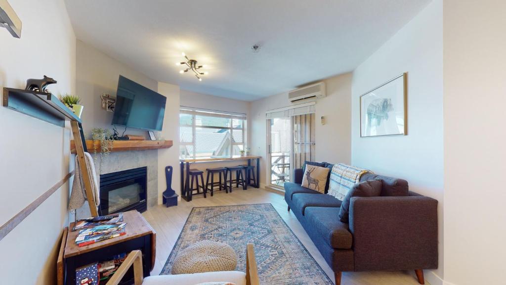 a living room with a blue couch and a fireplace at 1BR plus Den Village Condo with Mountain Views and Hot Tub by Harmony Whistler in Whistler