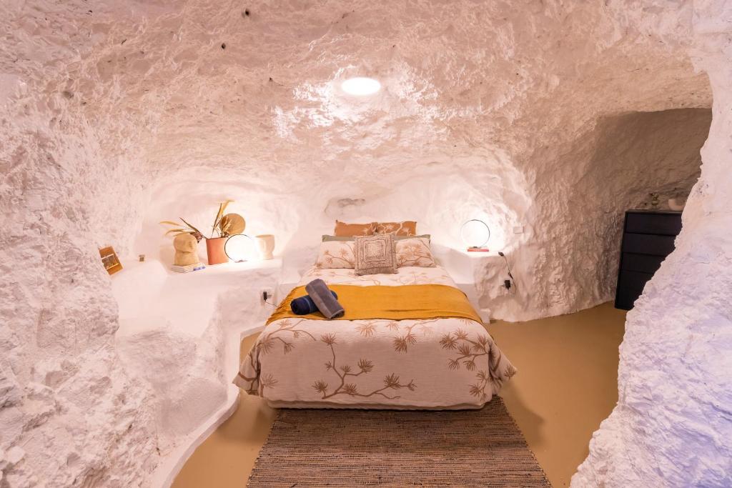 a bedroom with a bed in a fake rock wall at Daybreak Dugout Luxury Underground House in White Cliffs