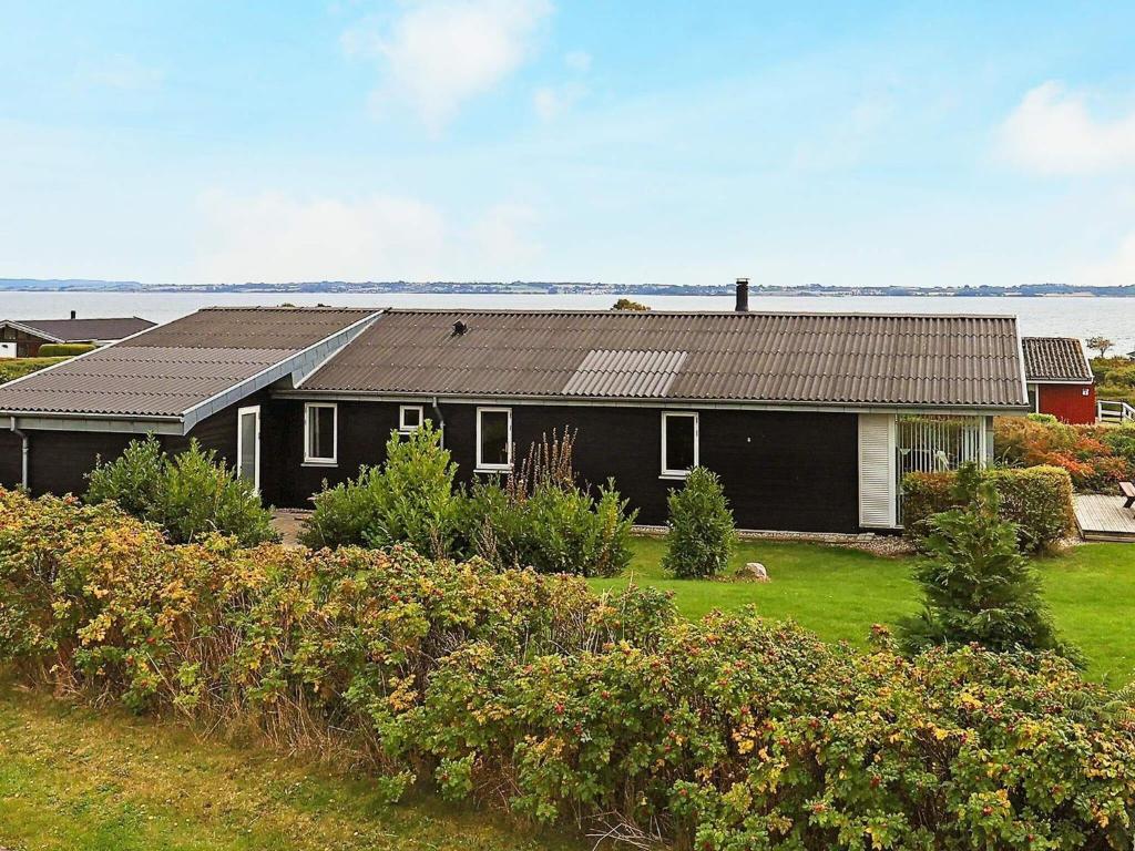 ein schwarzes Haus mit einem Garten mit Büschen in der Unterkunft Holiday home Ebberup VII in Ebberup