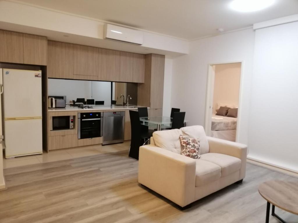 a living room with a white couch and a kitchen at 2-bedroom security apartment with free parking on premises in Riverwood