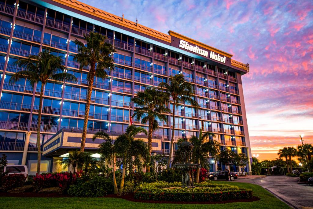 a hotel with palm trees in front of a building at Stadium Hotel in Miami Gardens