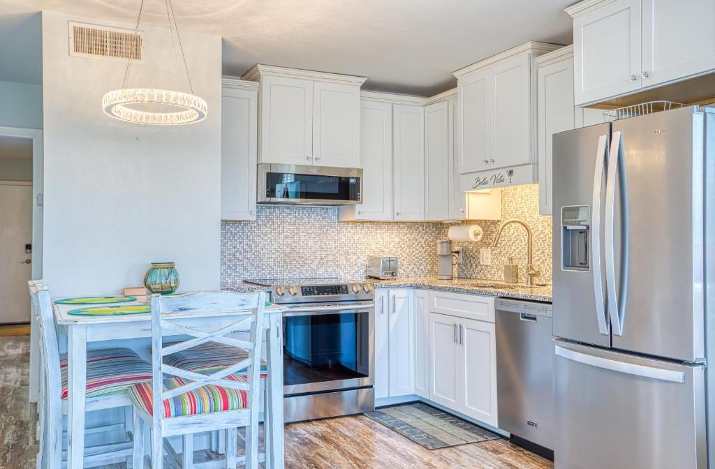 a kitchen with white cabinets and a stainless steel refrigerator at Bella Vista: Marshfront Condo 1 Block To The Beach. Pool & Hot Tub-1st Floor in Murrells Inlet