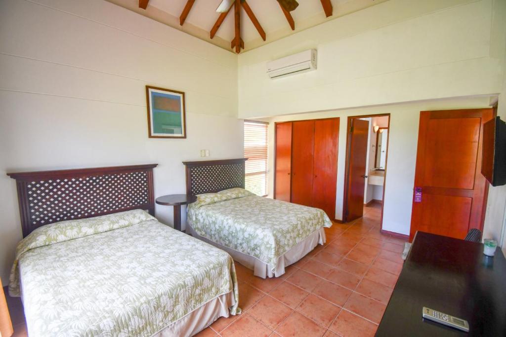a hotel room with two beds and a table at Costa Blanca Villas Lopez in Río Hato