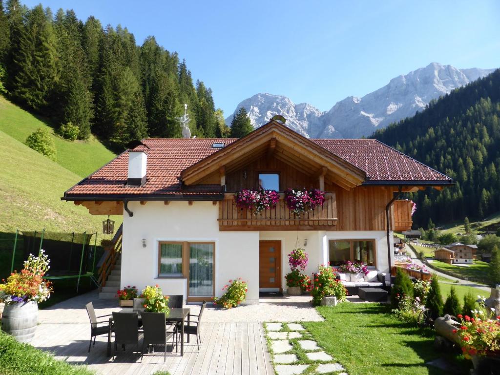 una casa en las montañas con mesa y sillas en Lüch da Mirió, en La Valle