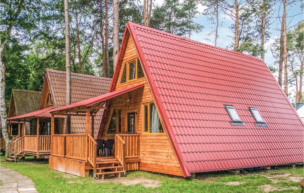 a large wooden cabin with a red roof at Gorgeous Apartment In Lukecin With Kitchen in Łukęcin
