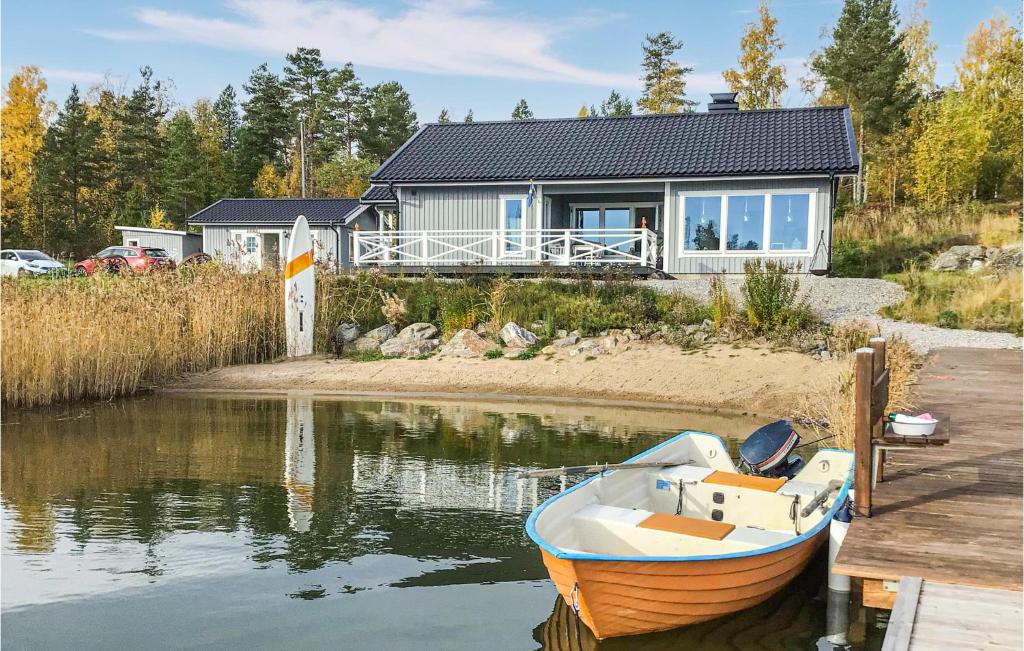 mała łódź siedząca na wodzie przed domem w obiekcie Gorgeous Home In Hudiksvall With Wifi w mieście Hudiksvall