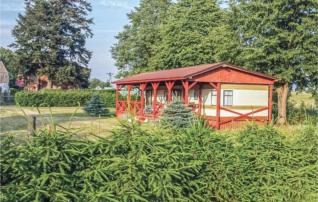 a small red building in a field with trees at Awesome Caravan In Retowo 4 With 2 Bedrooms in Gardna Wielka