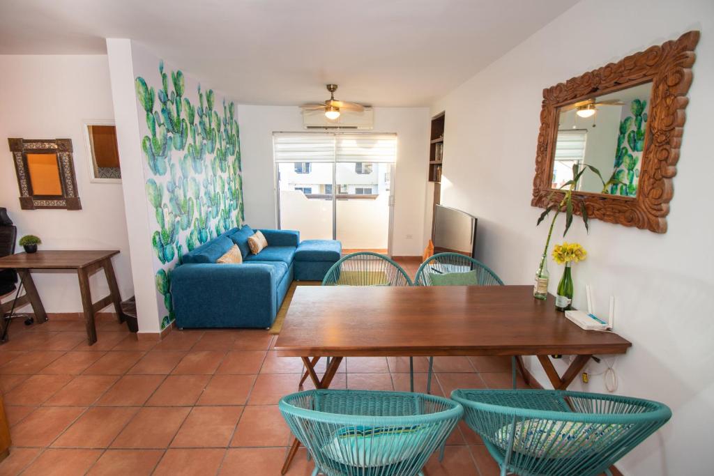 ein Wohnzimmer mit einem blauen Sofa, einem Tisch und Stühlen in der Unterkunft Your Cabo Penthouse Escape Walk to Sand & Sea! in Cabo San Lucas