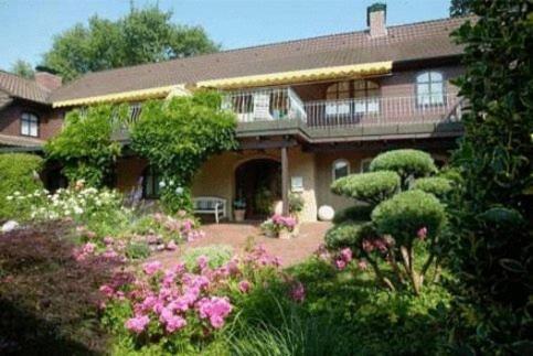 une grande maison avec un jardin de fleurs et de plantes dans l'établissement Hotel Garni Kristinenhof, à Bad Zwischenahn