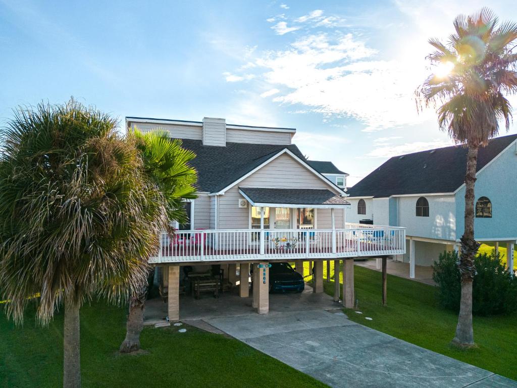 a large house with a deck and palm trees at Beach Mode ON! in Galveston