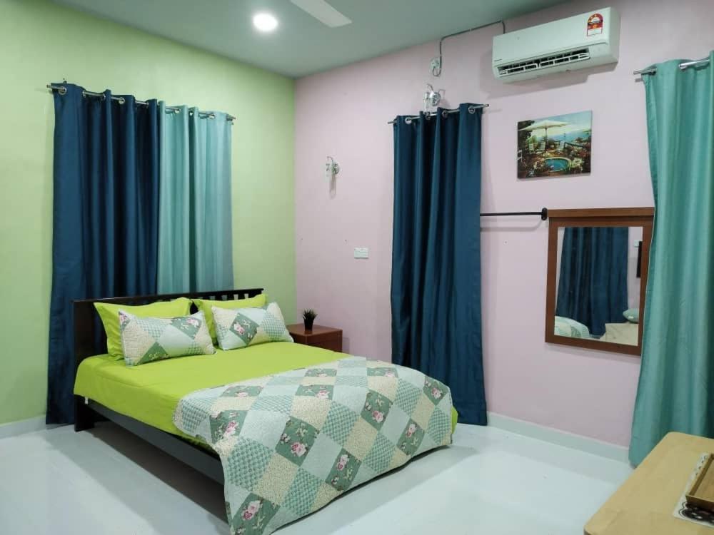 een slaapkamer met een groen bed en blauwe gordijnen bij Inap Desa 1 