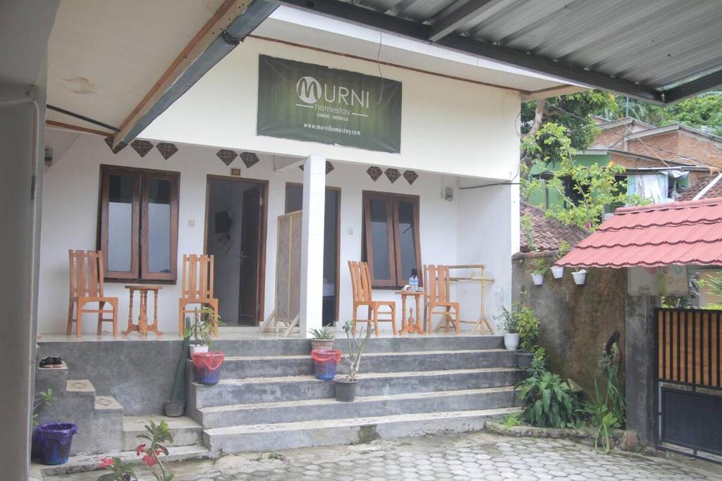 un porche de una casa con sillas y mesa en Mugeni Homestay, en Senggigi 