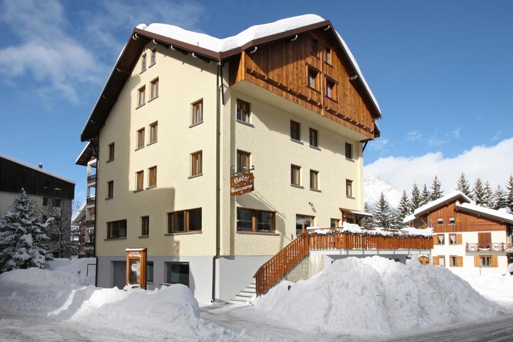 een gebouw met een sneeuwstapel ervoor bij Hotel Biancaneve in Sauze dʼOulx