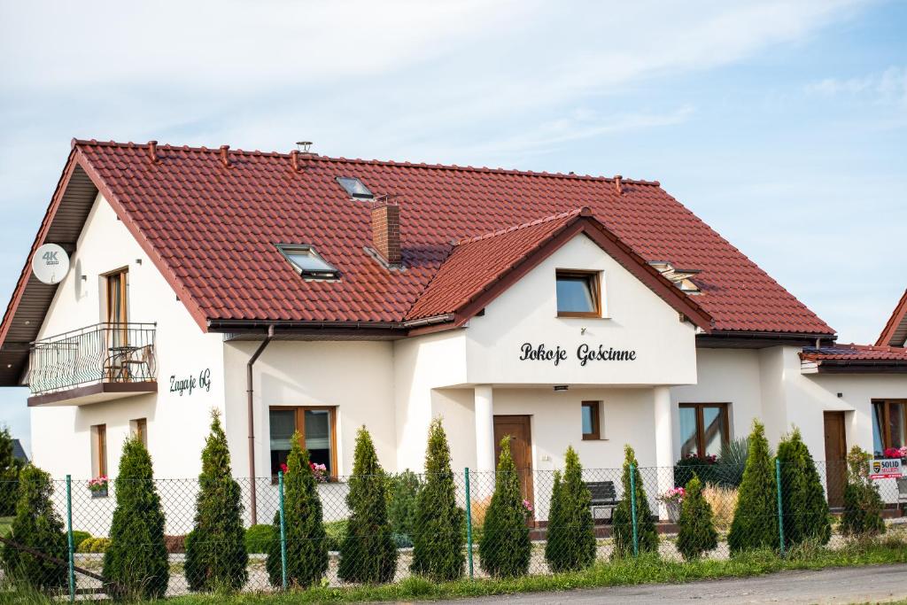 Biały dom z czerwonym dachem w obiekcie Zagaje Pokoje Gościnne w Sarbinowie