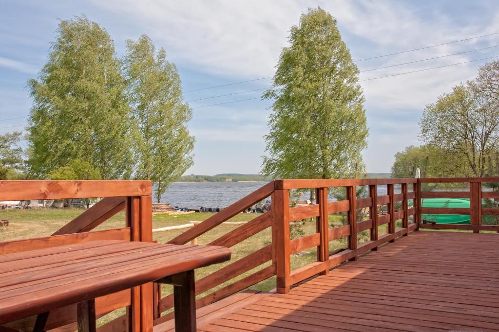 una terraza de madera con un banco y vistas al lago en Wilimy Domek przy plaży jeziora Dadaj en Biskupiec
