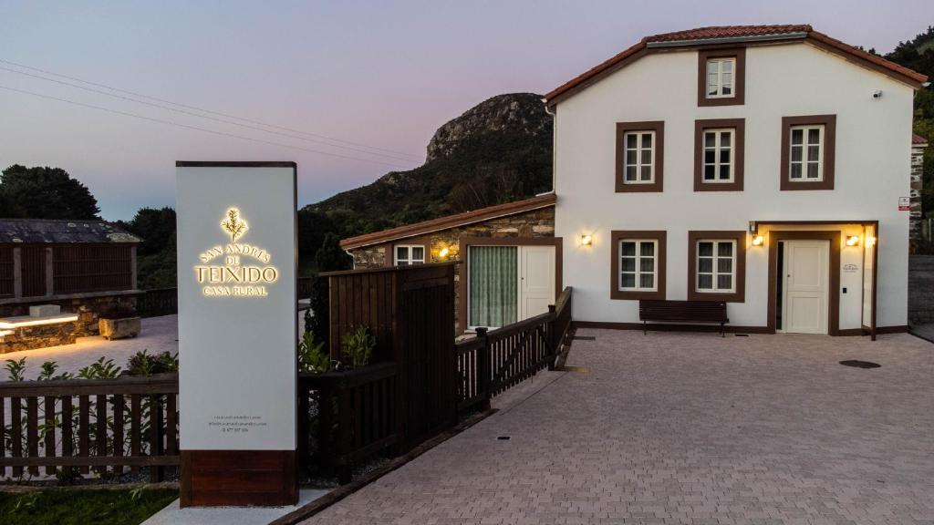 Uma casa branca com um cartaz à frente. em Casa Rural San Andrés de Teixido em Cedeira