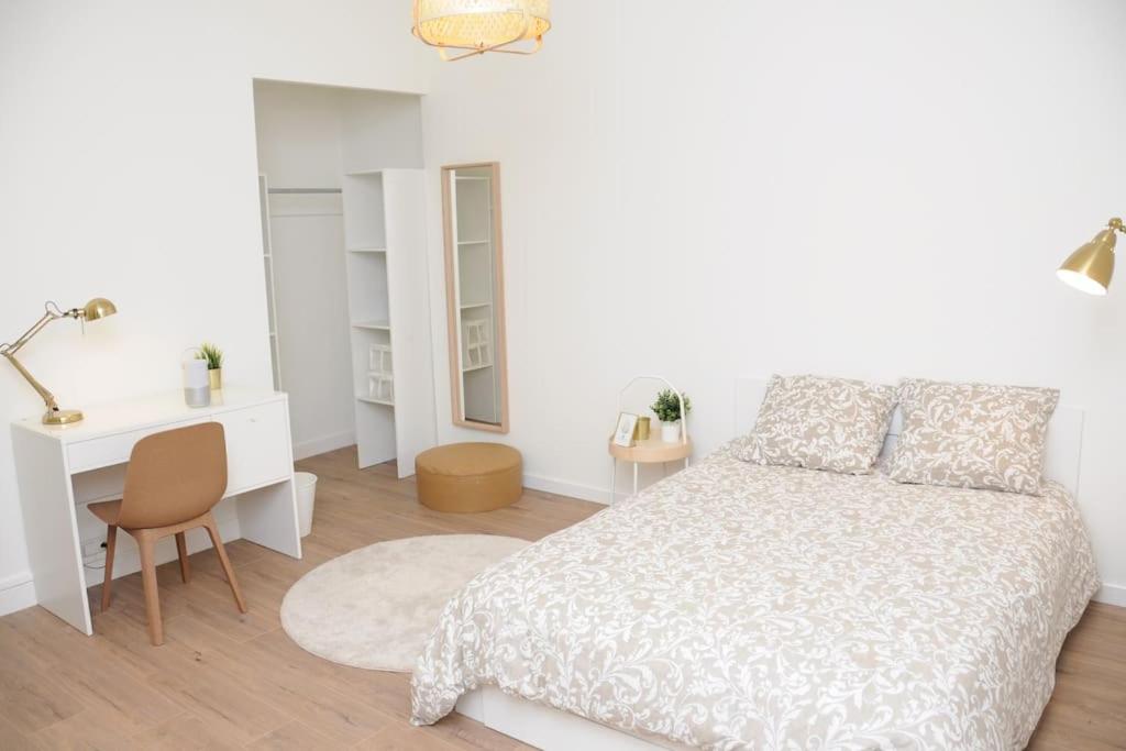 a white bedroom with a bed and a desk at Grand Appartement Confort in Vichy