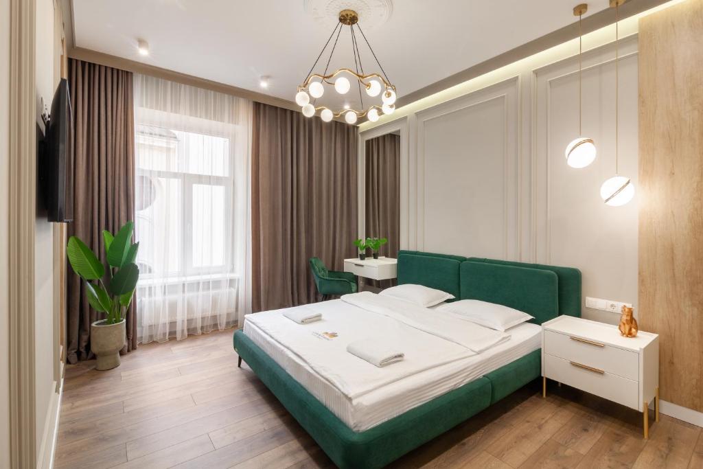 リヴィウにあるLEOGRAND VIP Apartments on Lesi Ukrainky 7のベッドルーム(緑のベッド1台、シャンデリア付)