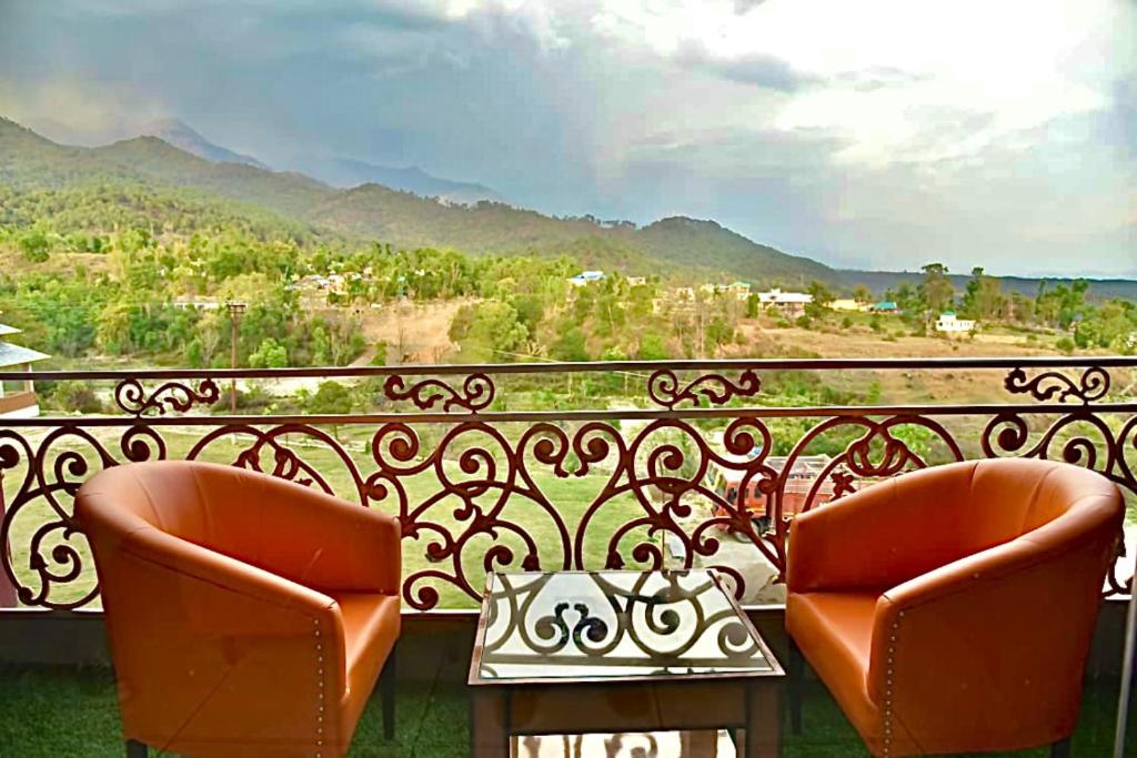 two chairs sitting on a balcony with a view at Jai Hotel By Boho in Pālampur