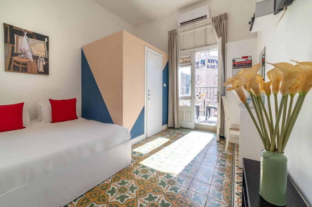 Un dormitorio con una cama blanca y un jarrón con flores en Paamonim Central Studios, en Jerusalén
