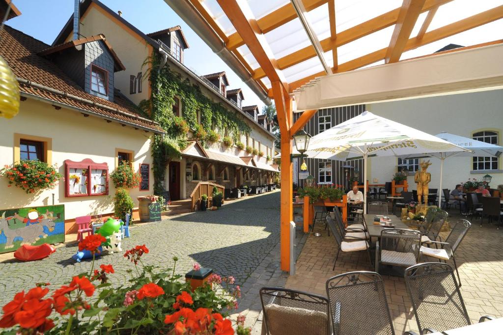 eine Außenterrasse mit Tischen, Stühlen und Blumen in der Unterkunft Hotel Zur Fernmühle in Ziegenrück