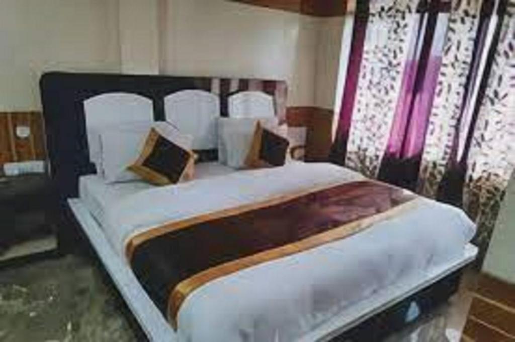 a bedroom with a large bed with white sheets and pillows at Hotel Diamond, Meerut in Meerut