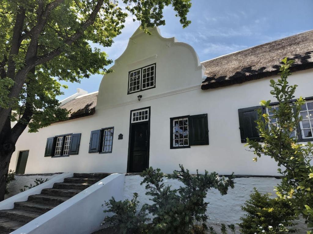 um antigo edifício branco com telhado de palha em Yellowwood House em Tulbagh