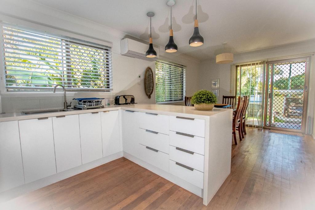 an open kitchen with white cabinets and a dining room at Holiday House in Brisbane