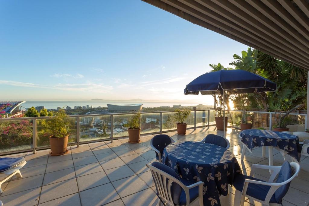 a balcony with tables and chairs and a view of the ocean at Villa Marina Guest House in Cape Town