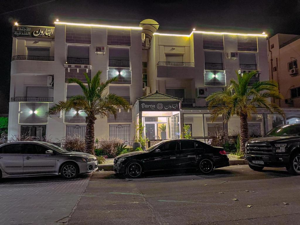 dois carros estacionados num parque de estacionamento em frente a um edifício em Baron Palace hotel suites em Aqaba