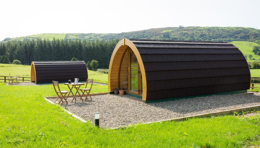 um pequeno edifício de madeira com uma mesa num campo em Kilbane Glamping em Kilbane