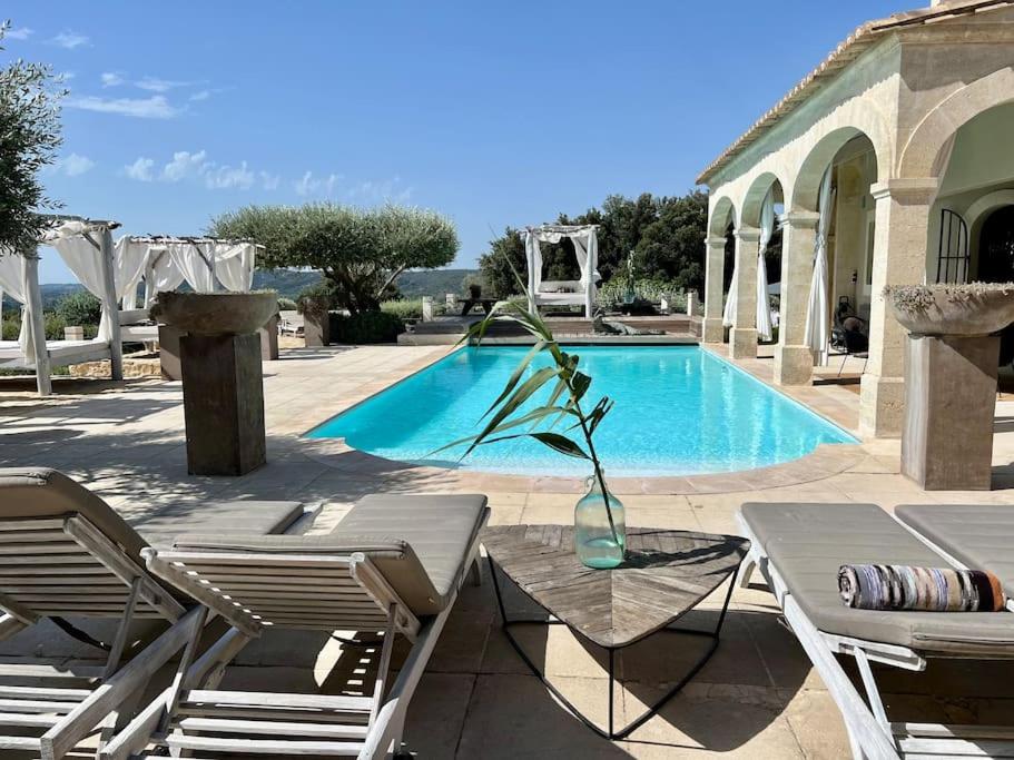 Luxury Villa in front of the famous Pont-du-Gard. في كاستيون-دو-غارد: مسبح مع طاولة وكراسي ومزهرية مع نبات