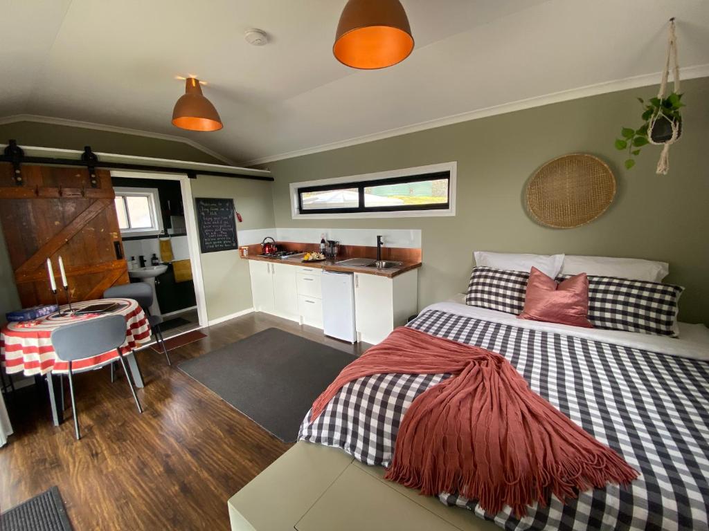 ein kleines Schlafzimmer mit einem Bett und einer Küche in der Unterkunft Tiny Home on a Hill in Heathcote