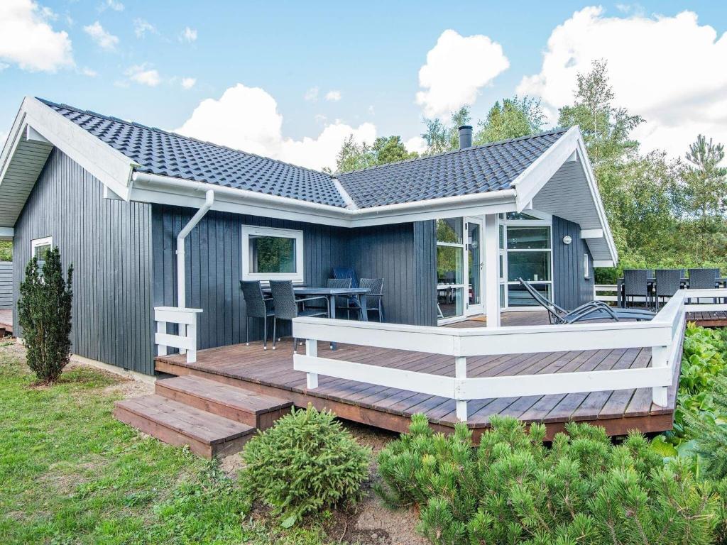 a house with a wooden deck with a table at 8 person holiday home in Ebeltoft in Ebeltoft