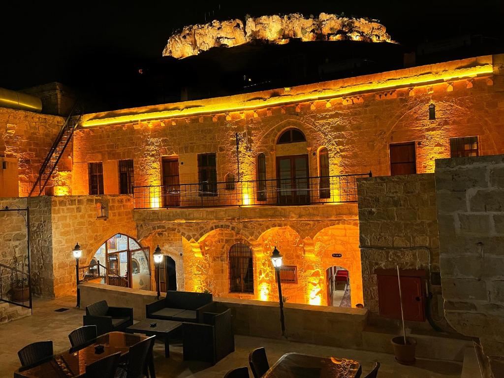 un grand bâtiment en briques avec des lumières allumées la nuit dans l'établissement Fairouz Konak Otel, à Mardin