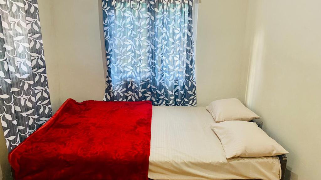 una piccola camera da letto con tende blu e un letto con una coperta rossa di Misty Mud House a Idukki