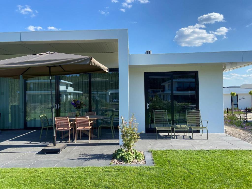un patio con sombrilla, mesa y sillas en Modern villa in Harderwold with garden, en Zeewolde