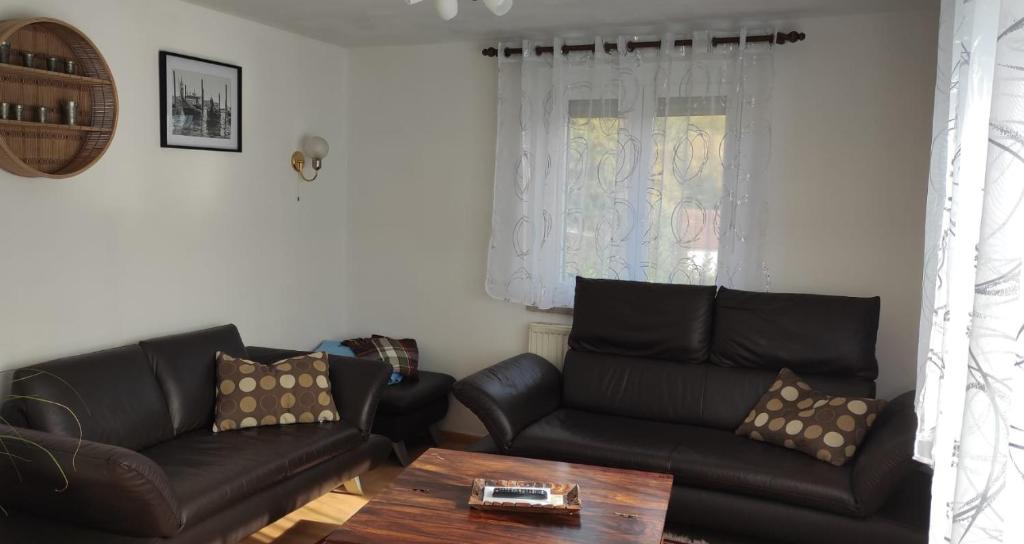 ein Wohnzimmer mit schwarzen Ledersofas und einem Tisch in der Unterkunft Wörnitz Haus mit 3 Schlafzimmern in Oettingen in Bayern