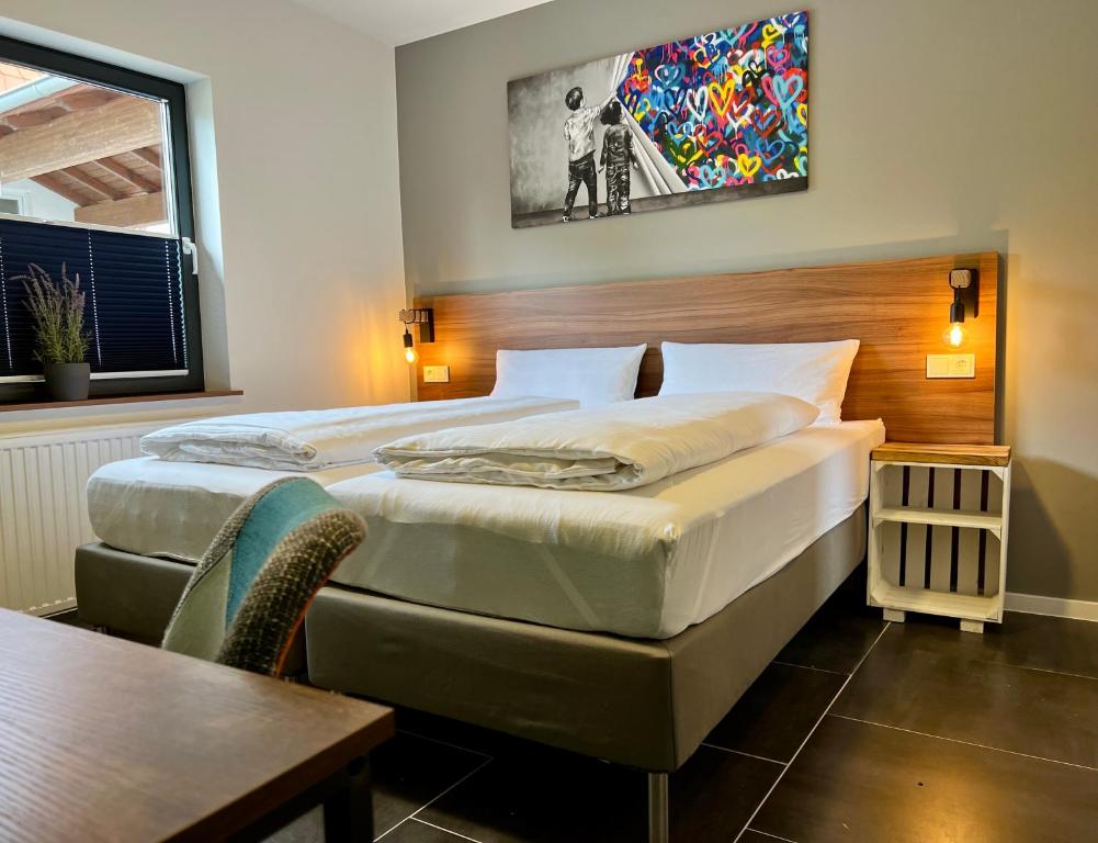 um quarto com 2 camas, uma mesa e um quadro em JUNIPRO Apartments & Rooms em Nohfelden