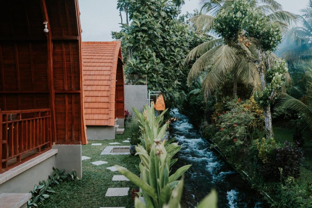 a garden with a stream in the middle of a house at Kubu River View in Ambengan