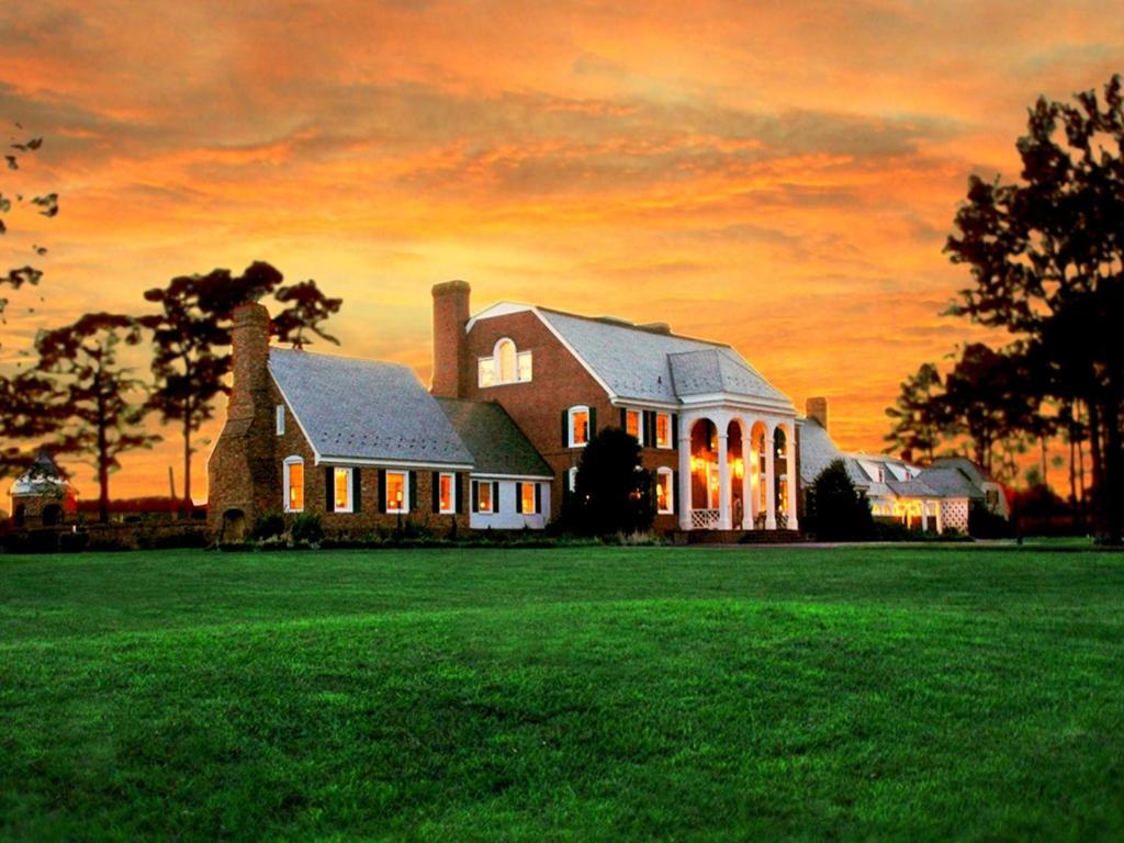 a large house on a field with a sunset at Kingsbay Mansion and Vacation Rental Houses in Marion