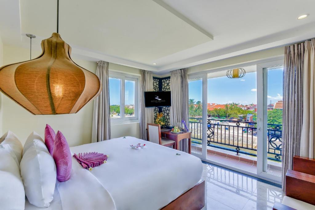 1 dormitorio con 1 cama y balcón en River Suites Hoi An, en Hoi An