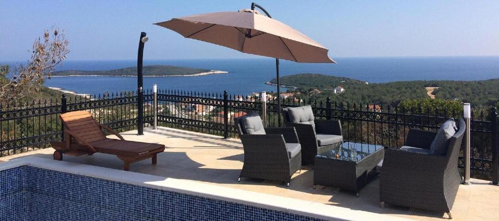 un patio con sillas, una sombrilla y el océano en Villa magic en Rukavac