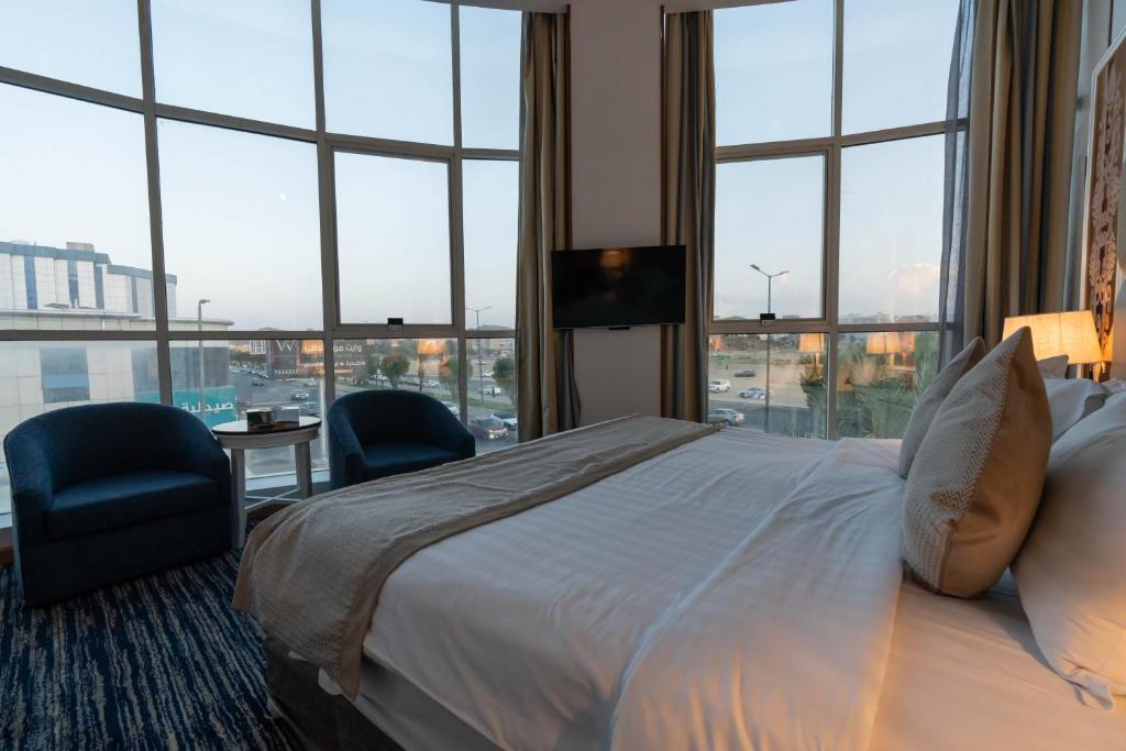pokój hotelowy z łóżkiem, krzesłami i oknami w obiekcie Platinum Al Khamseen w mieście Taif
