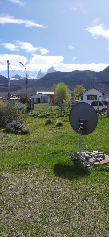 una antena parabólica sentada en un campo de hierba en Nativos en El Chaltén